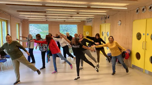 A dance class with members stretching their arms and legs in the hall