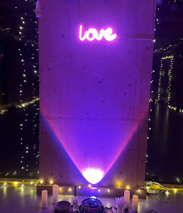 A glowing neon love sign above candles and fairy lights in the hall at an Ecstatica night